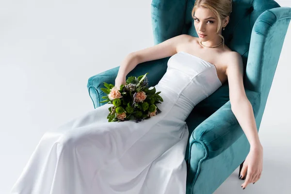 穿着雅致婚纱 手持鲜花 坐在白色扶手椅上的新娘高角镜 — 图库照片