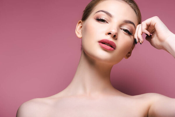 naked and young woman with makeup looking at camera on pink 