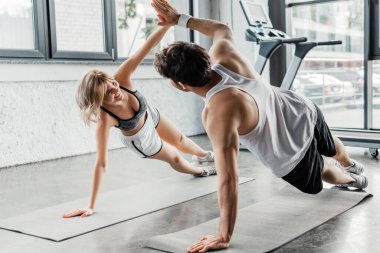 Sporcu ve neşeli sporcu kadın spor paspasları üzerinde egzersiz yaparken beşlik çakıyor. 
