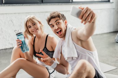 Seçici odak noktası, neşeli bir adamın barış işareti göstermesi ve kızla selfie çektirmesi