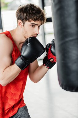 Boks eldivenli sporcunun kum torbasıyla egzersiz yaptığı seçici odak noktası. 