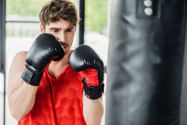 Boks eldivenli atletik bir adamın kum torbasıyla egzersiz yaptığı seçici odak noktası. 