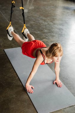 Spor giyimli atletik bir kadının direniş bantlarıyla egzersiz yaparken kalas kullanmasının seçici odağı.