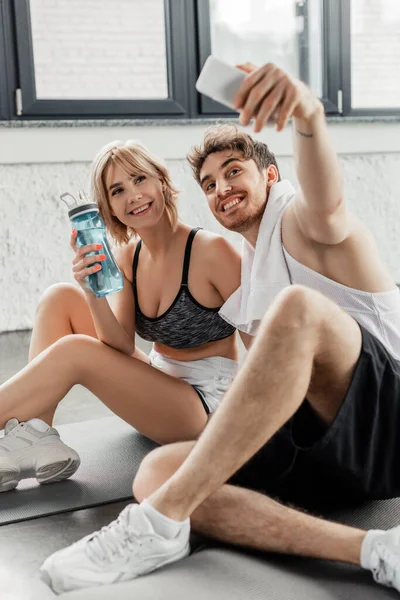 selective focus of happy sport couple taking selfie in sports center