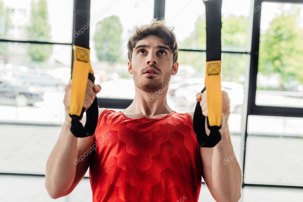 handsome and young sportsman working out with elastics in gym 