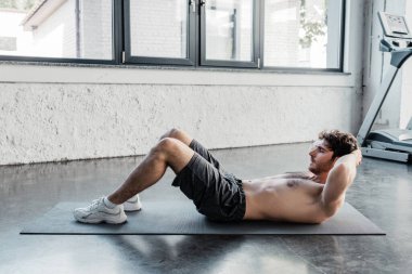 Üstsüz sporcunun spor salonundaki spor minderinde mekik çekişi. 