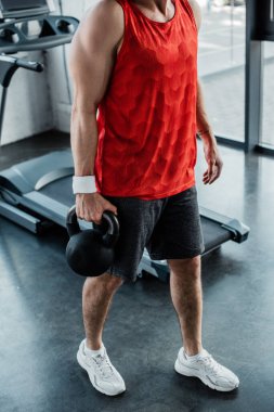 Spor merkezinde ağır dambıllar tutan güçlü bir adamın görüntüsü. 