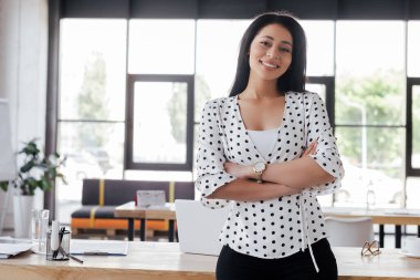Ofiste kollarını kavuşturmuş neşeli iş kadını