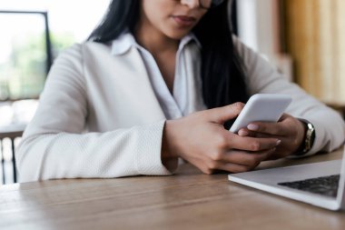 Bilgisayarın yanında akıllı telefon kullanan iş kadını görüntüsü 