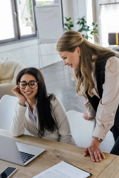 Selective Focus Happy Businesswoman Standing Attractive Coworker Glasses Looking Laptop — Stock Photo, Image