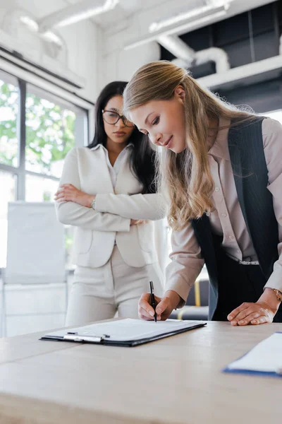Selective Focus Attractive Businesswoman Signing Contract Coworker Crossed Arms — Stock Photo, Image