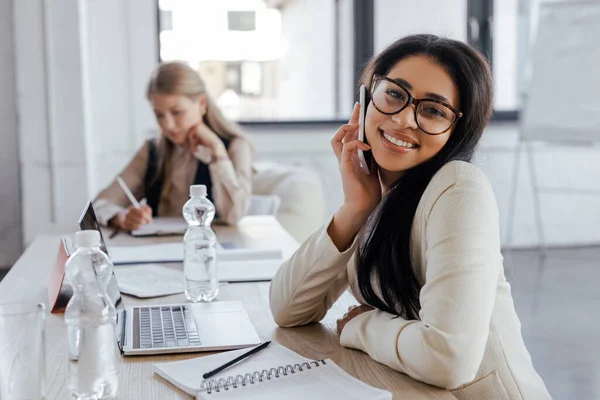 Selective Focus Happy Businesswoman Glasses Talking Smartphone Laptop Coworker — Stock Photo, Image