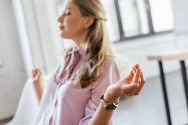 Ofiste meditasyon yapan, gözleri kapalı güzel bir iş kadınının seçici odağı. 
