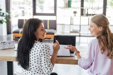 İş arkadaşı ve dizüstü bilgisayarın yanındaki Stylus 'u işaret eden mutlu iş kadını. 