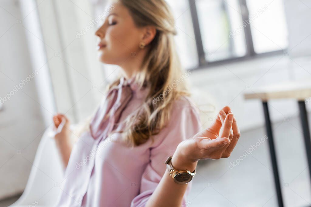 selective focus of pretty businesswoman with closed eyes meditating in office 