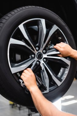 cropped view of technician touching wheel disk while fixing car clipart