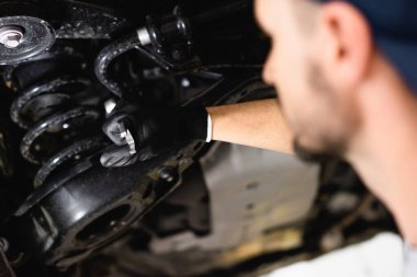 selective focus of mechanic holding wrench while fixing vehicle  clipart