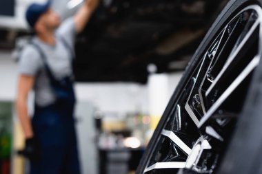 Servis merkezinde tamircinin yanında seçici odaklı yeni araba lastiği 