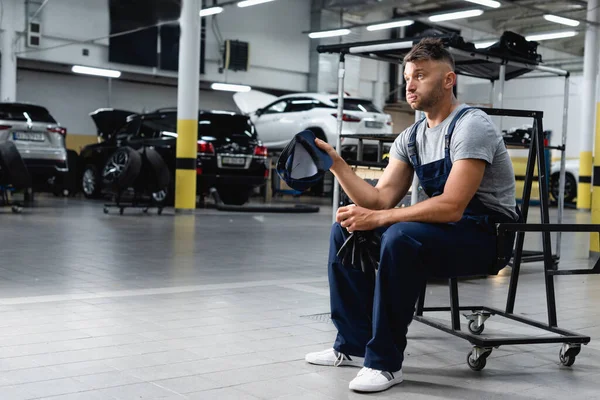 Tired Technician Overalls Holding Cap Gloves While Sitting Cars Workshop — Stock Photo, Image