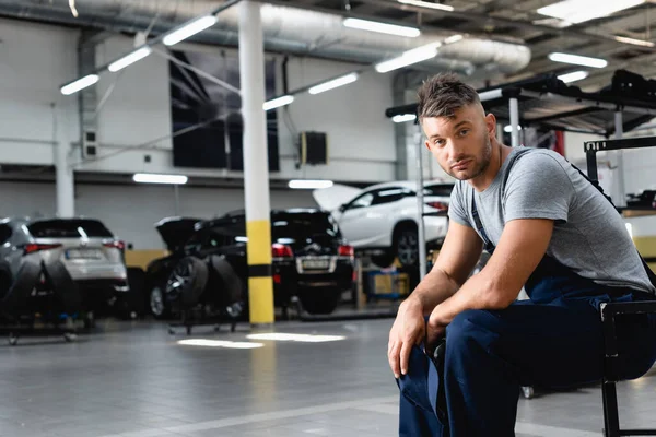 Tired Technician Overalls Holding Cap Looking Camera While Sitting Cars — Stock Photo, Image