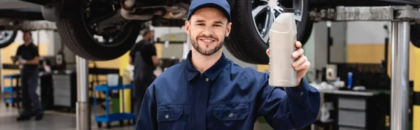 Panoramatický Záběr Šťastný Mechanik Uzávěru Drží Láhev Automobilovým Olejem — Stock fotografie
