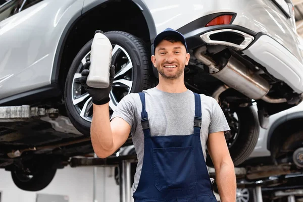 Niski Kąt Widzenia Szczęśliwy Mechanik Nakrętce Trzymając Butelkę Olejem Samochodowym — Zdjęcie stockowe