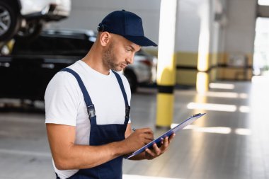 Elinde dosya tutan üniformalı yakışıklı bir tamirci.