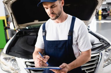 Servis istasyonunda açık kaputun yanındaki panoya otomatik mekanik yazma