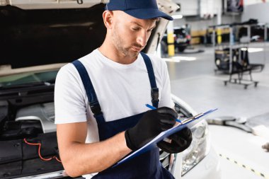 Servis istasyonunda açık kaputun yanındaki panoya otomatik mekanik yazma