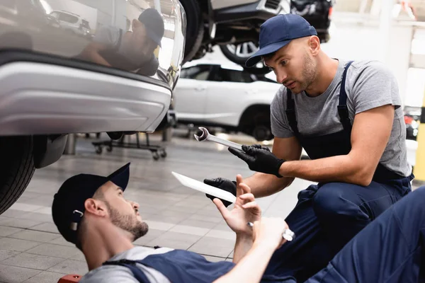 Selective Focus Mechanic Uniform Holding Digital Tablet Giving Wrench Coworker — Stock Photo, Image