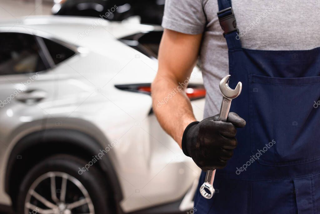 cropped view of mechanic in latex glove holding wrench 