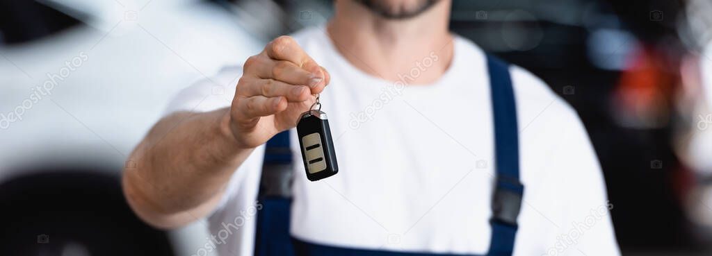 horizontal crop of mechanic in uniform holding car key 