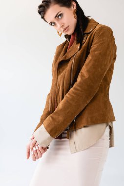 Süet ceketli güzel, şık bir kız. Gri renkli kameraya bakıyor.