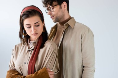 Yakışıklı, şık bir adam. Gri renkli bir kadının yanında duruyor.