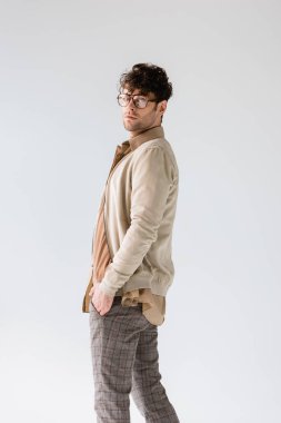 Yakışıklı, modaya uygun bir adam gri üzerinde el ele tutuşurken kameraya bakıyor.