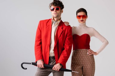 Çekici, şık bir kız. Gri üzerinde kapalı şemsiyeli şık bir adamın omuzuna dokunuyor.