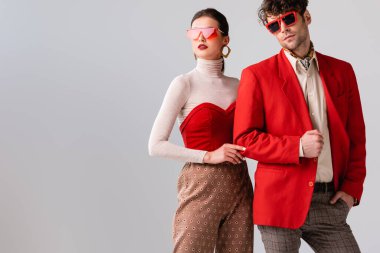 Gri renkli elbiseli ve güneş gözlüklü genç, modaya uygun bir çift.