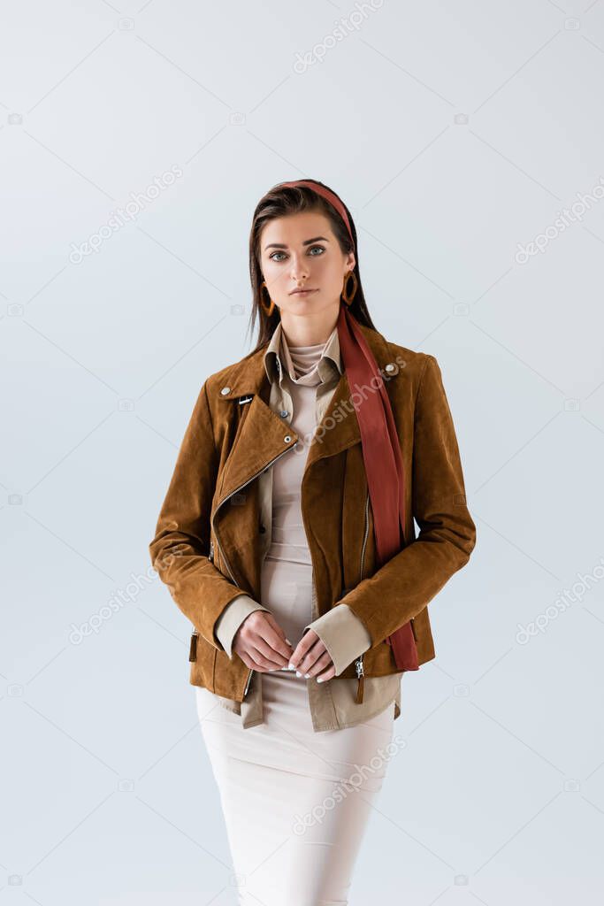 Front view of beautiful woman in autumn outfit looking at camera isolated on grey 