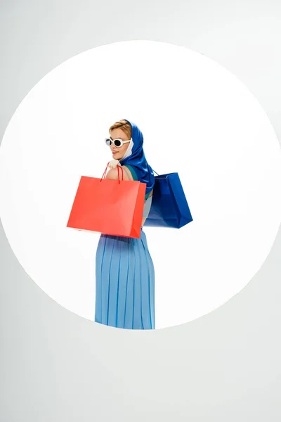Вид Улыбающуюся Женщину Платке Солнцезащитных Очках Держащую Красные Синие Сумки — стоковое фото