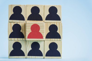square of wooden blocks with black and red human icons on blue background, leadership concept  clipart