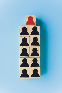 Mavi arka planda siyah ve kırmızı insan simgeleri olan tahta blokların üst görünümü, liderlik kavramı