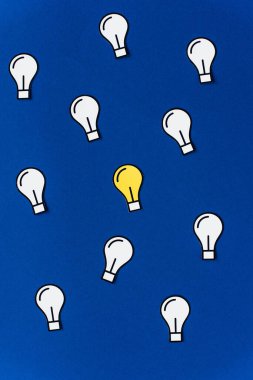 top view of paper light bulbs on blue background, business concept clipart