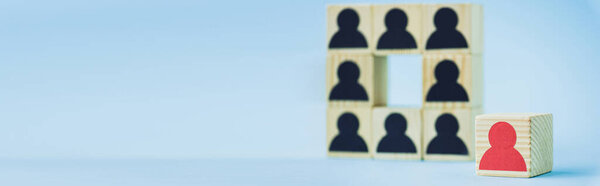 квадрат деревянных блоков с черными человеческими иконами и красной фигурой на синем фоне, селективная фокусировка, панорамный снимок