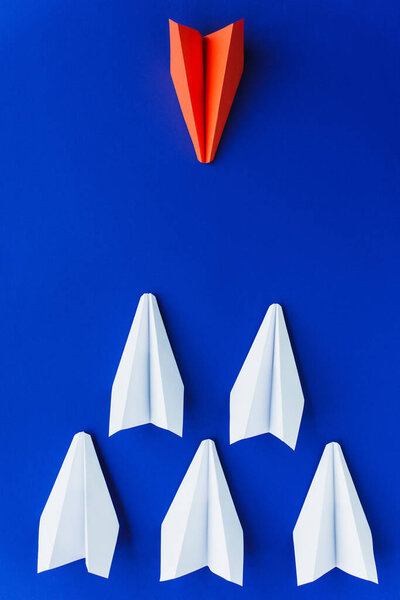 flat lay with white and red paper planes on blue background, leadership concept 