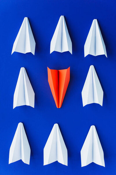 flat lay with white and red paper planes on blue background, leadership concept 