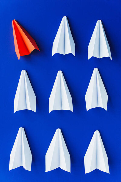 flat lay with white and red paper planes on blue background, leadership concept 
