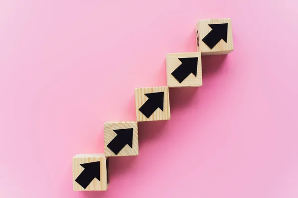 粉色背景的黑色箭头木制方块顶部视图 商业概念 — 图库照片