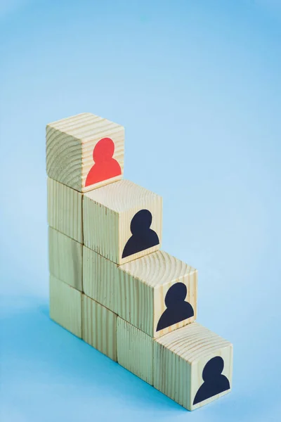 Pyramid of wooden blocks with black and red human icons on blue background, leadership concept — Stock Image Pyramid Wooden Blocks Black Red Human Icons Blue Background Leadership Stock Image