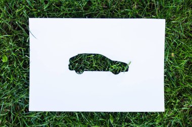Top view of paper with car sign on green grass, ecology concept clipart