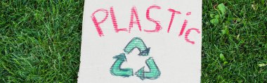 Plastik harflerin yatay mahsulü ve yeşil çimlerin üzerinde geri dönüşüm tabelası, ekoloji kavramı.